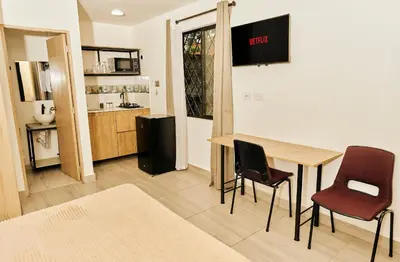 a room with a table and two chairs and a kitchen at Apartahotel Castellana in América