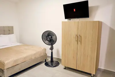 a bedroom with a bed and a fan next to a cabinet at Apartahotel Castellana in América