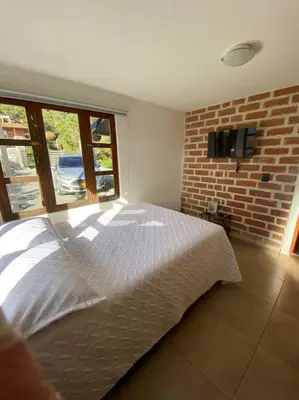 a bedroom with a white bed and a brick wall at Casa de Campo completa ubicada en Santa Elena in Santa Elena