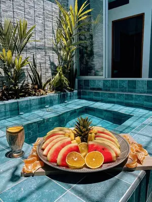 a plate of fruit on a table next to a swimming pool at Casa de Verano Altos de la Colina-Doradal in Doradal