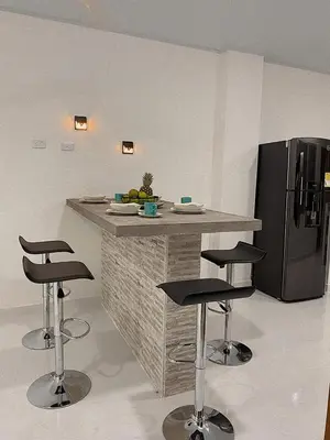 a kitchen with a counter with stools and a refrigerator at Casa de Verano Altos de la Colina-Doradal in Doradal