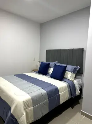 a bedroom with a large bed with blue pillows at Hermoso Apartamento Entero in Itagüí