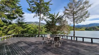a table and chairs on a deck next to a lake at Casa de Campo PREMIUN in Guatapé