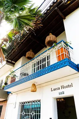 a white building with blue balconies and palm trees at Lucca Hostel Medellín in Medellín