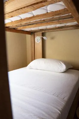 a bunk bed with white pillows on top of it at Lucca Hostel Medellín in Medellín