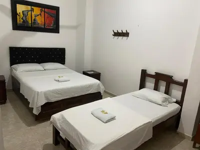 two beds in a room with white sheets at Hotel Boyaca in Puerto Boyacá