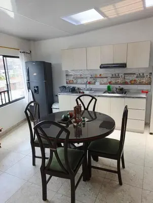 a kitchen with a table and chairs and a refrigerator at Comodas y agradables Habitaciones en Chipre in Manizales