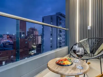 a table with a plate of food and wine glasses on a balcony at Apto nuevo, elegante y cómodo in Medellín