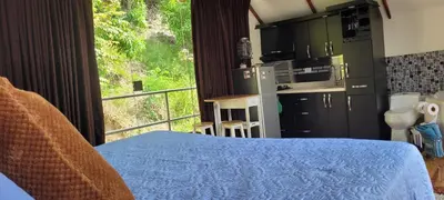 a room with a bed and a kitchen with a window at Cabaña en el Aire con jacuzzi a 5min del Pueblo in Sopetran