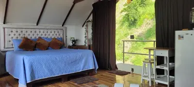 a bedroom with a blue bed and a large window at Cabaña en el Aire con jacuzzi a 5min del Pueblo in Sopetran