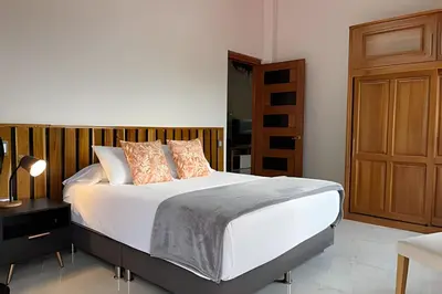 a bedroom with a white bed with a wooden headboard at Casa Palos Altos; Poblado; 6 min de Provenza; in El Poblado