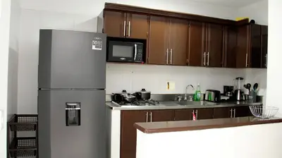 a kitchen with a stainless steel refrigerator and wooden cabinets at Verde Primavera in Guayaquil