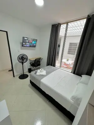a bedroom with a bed and a window and a chair at Verde Primavera in Guayaquil