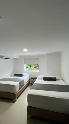 two beds in a white room with a window at Hotel Medellín 66 in Medellín