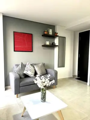 a living room with a couch and a table with flowers at El Tesoro Apto in Poblado in El Poblado