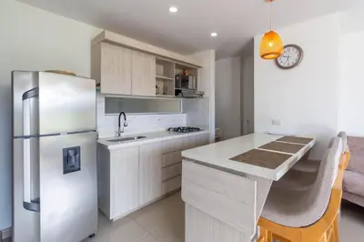 a kitchen with a stainless steel refrigerator and a table at Mountain View Pool & Slide AC 5min to Town in Santa Fe de Antioquia