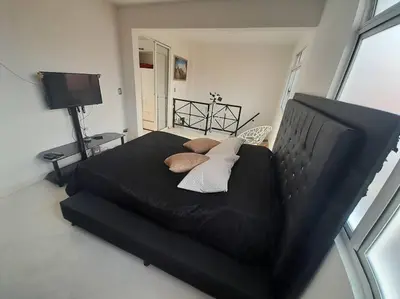 a bedroom with a black bed with pillows and a television at Dúplex con hermosa vista a la ciudad deck exterior in Itagüí