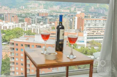 a table with two glasses of wine and a bottle at Charming Decor & Stunning Views Green Poblado in Medellín