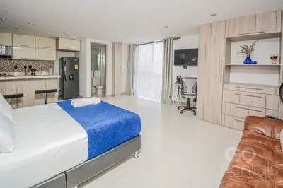 a bedroom with a large bed and a kitchen at Charming Decor & Stunning Views Green Poblado in Medellín
