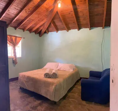 a bedroom with a bed and a blue chair at ByB Casa campestre in Riochico Pérez