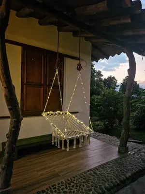 a hanging chair with lights hanging from a house at Caminos Alojamiento in Jardin