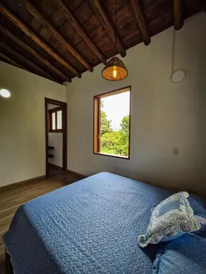 a bedroom with a blue bed with a window at Caminos Alojamiento in Jardin