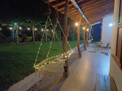 a swing hanging from a porch at night at Caminos Alojamiento in Jardin