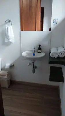 a bathroom with a sink and a toilet and towels at Caminos Alojamiento in Jardin