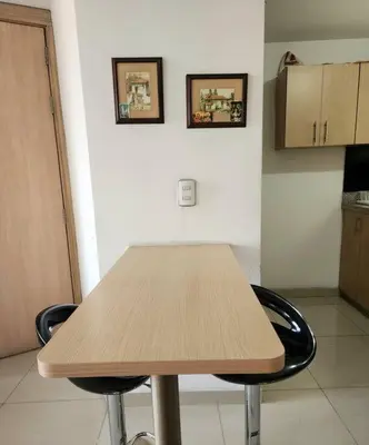 a wooden table in a kitchen with two pictures on the wall at Vivienda Céntrica y Acogedora in Sabaneta