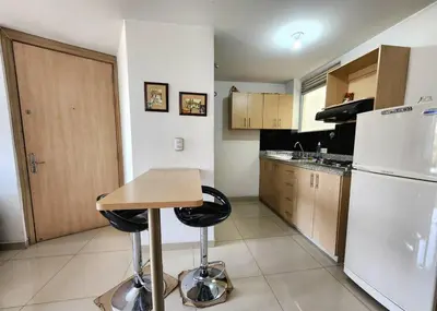 a kitchen with a table and a white refrigerator at Vivienda Céntrica y Acogedora in Sabaneta