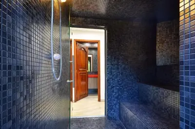 a bathroom with a walk in shower with blue tiles at Stunning Luxury Penthouse with SPA and Concierge in Medellín