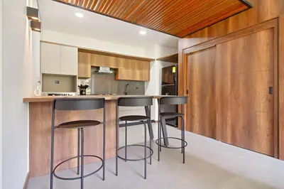a kitchen with wooden cabinets and bar stools at Apartamento exclusivo, edificio moderno, gran balcon y linda vista in El Poblado