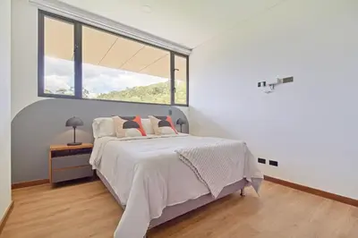 a white bedroom with a bed and a large window at Apartamento exclusivo, ideal para familias grandes con una vista sensacional in Medellín