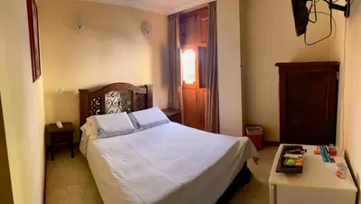 a bedroom with a white bed and a table at Hotel Colonial Aguadas in Aguadas