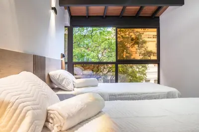 a bedroom with two beds and a large window at Modern Central Apt Laureles Medellin With 3 ACs in Medellín