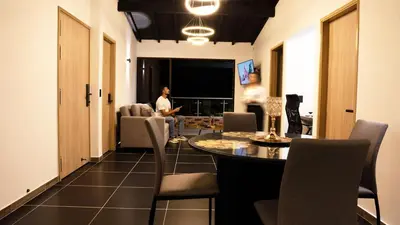 a person sitting in a living room with a table and chairs at Modern Central Apt Laureles Medellin With 3 ACs in Medellín