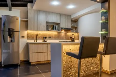 a kitchen with a refrigerator and a counter with chairs at Modern Central Apt Laureles Medellin With 3 ACs in Medellín