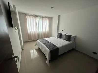 a white bedroom with a bed and a television at Apartamento Nuevo Laureles- La 70 in Medellín