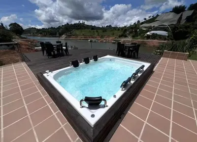 a jacuzzi tub on a patio next to a lake at Finca con jacuzzi a 15min de Guatape in El Peñol