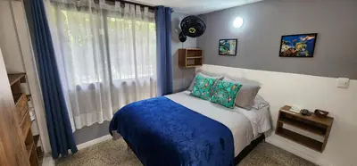 a bedroom with a bed with a blue blanket and a window at Casa de las Palmas 1 in Medellín