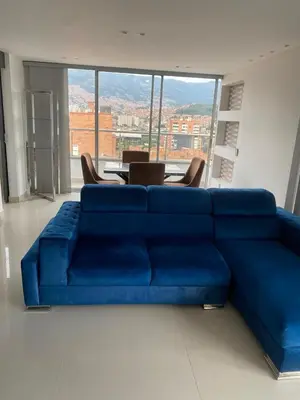 a blue couch in a room with a table and chairs at Hermoso y nuevo apartamento 2 in Medellín