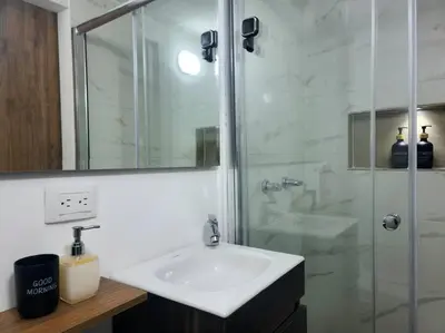 a white bathroom with a sink and a shower at Casa de las Palmas 2 in Guayaquil