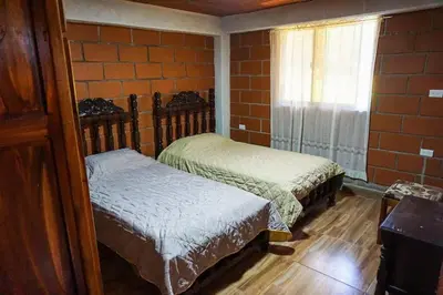 two beds in a room with a brick wall at Retro Finca Urrao - Peaceful Avocado Farm Retreat in Urrao