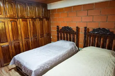 two beds in a bedroom with wooden cabinets and a brick wall at Retro Finca Urrao - Peaceful Avocado Farm Retreat in Urrao