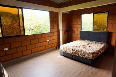 a bedroom with a bed in a room with two windows at Retro Finca Urrao - Peaceful Avocado Farm Retreat in Urrao