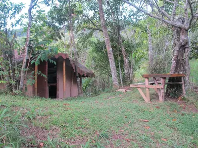 a wooden bench next to a shed in the woods at Cabaña en reserva natural in San Rafael