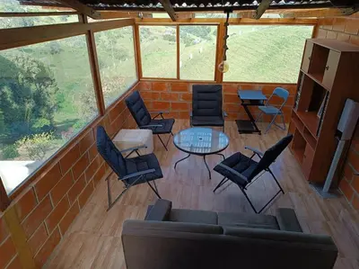 a screened in porch with a couch and chairs and a table at Casa de campo in Jericó