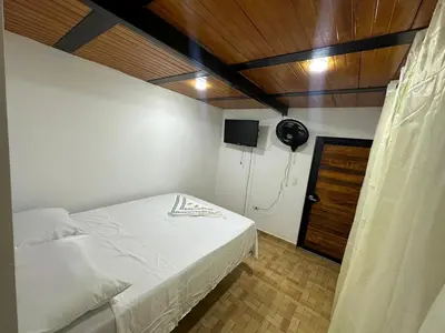 a bedroom with a bed and a room with a fan at ECOHOTEL MONTEBELLO Norcasia Caldas in Confines