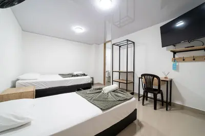 a bedroom with two beds and a table and a chair at Hotel Doxa in Medellín