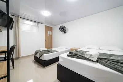 a room with two beds and a television in it at Hotel Doxa in Medellín